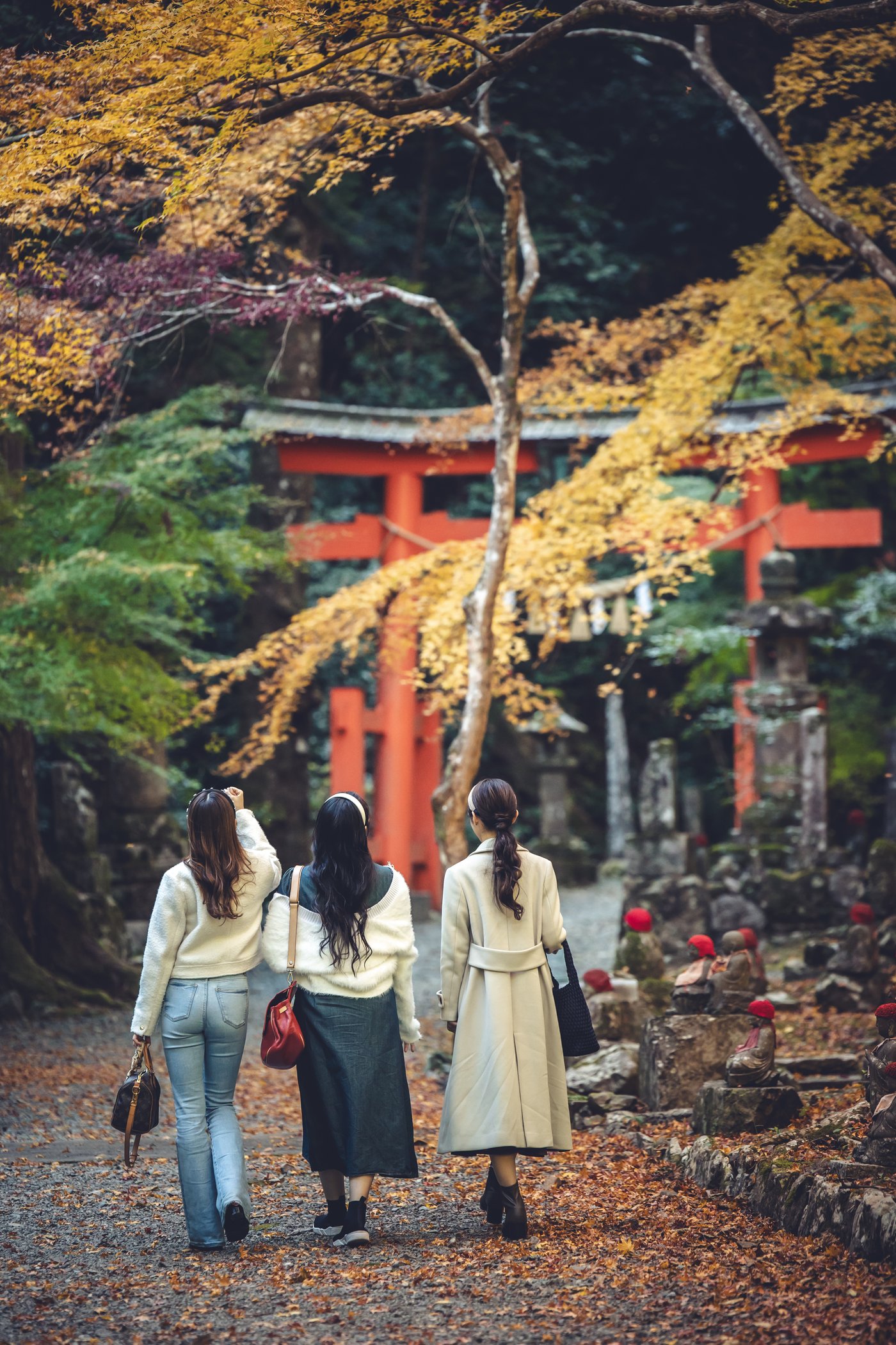 紅葉と赤い建物を眺めながら歩く3人の後ろ姿