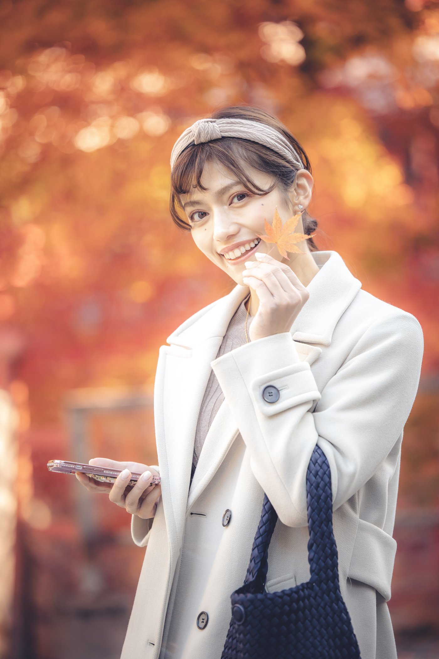オレンジ色の紅葉を背景に笑顔を見せる旅行者