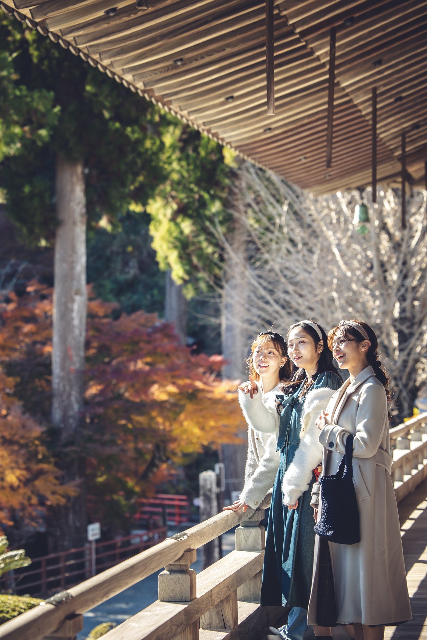 屋根の下から紅葉の庭を眺める3人