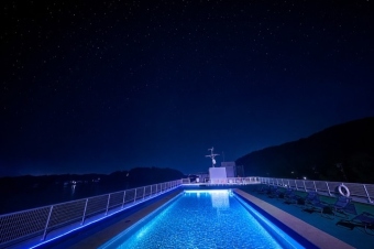 夜空と青くライトアップされた屋上スカイプール